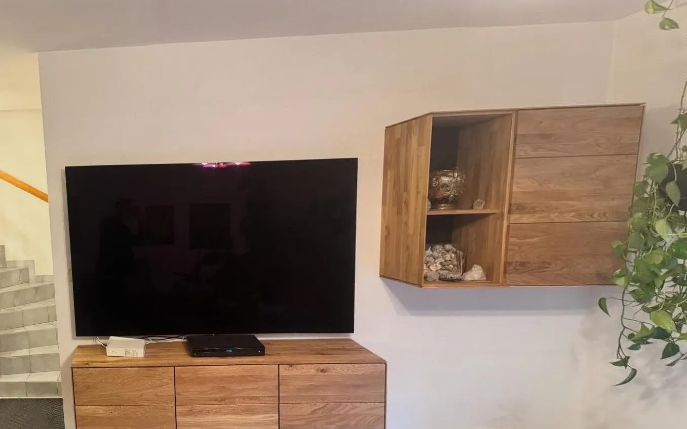 Vorher: Wohnzimmerwand vor dem Anstrich: weiße Wand hinter TV und Eichenmöbel