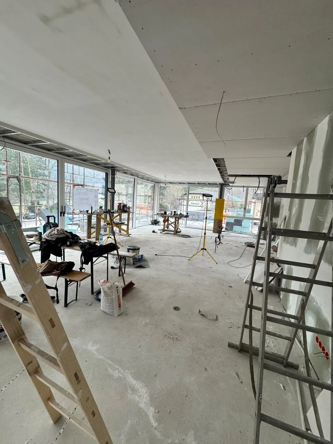 Frisch gespachtelte Decke im Neubau, Leitern und Gerüst im Raum