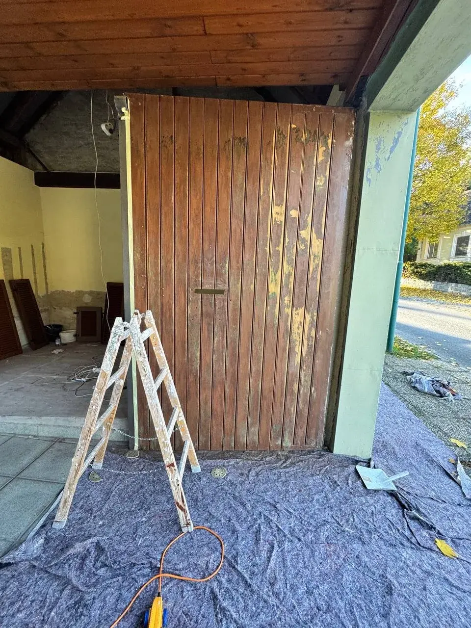 Abgeklebtes Holztor während der Arbeiten, Leiter und Abdeckvlies